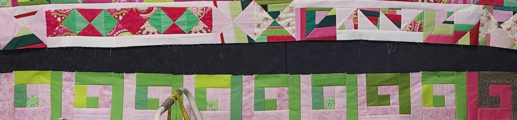 Two rows of the pink and green in-progress quilt top. These rows have no sashing but are place on an almost-black background to show what dark sashing would look like.