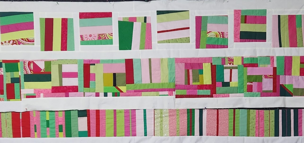 A pink and green in-progress quilt top set in rows. The three rows are separated with white sashing.