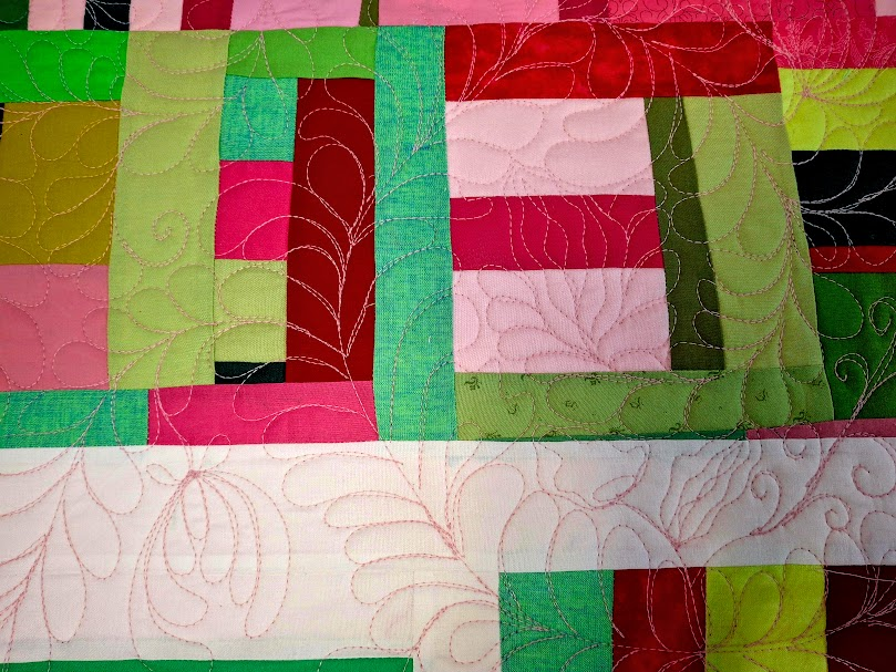 Picture of improv quilt in red, pink, green. Improv quilting of feathers, scrolls, and flowers. 