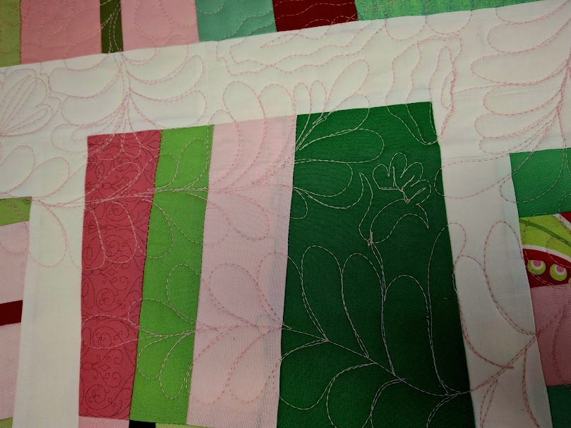 Picture of improv quilt in red, pink, green. Improv quilting of feathers, scrolls, and flowers. 