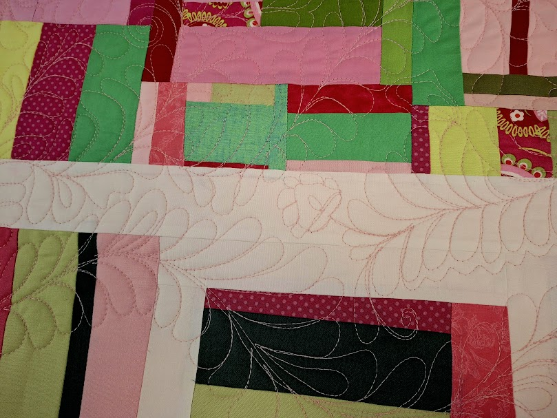 Picture of improv quilt in red, pink, green. Improv quilting of feathers, scrolls, and flowers. 