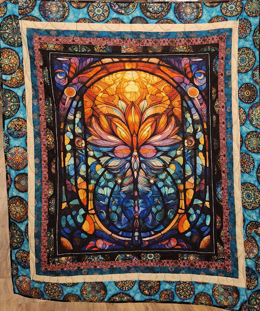 One of five quilts made by the Cotton Quilters Guild. This one began with a panel. The quilter added four rounds of sashing to enlarge the panel to lap size.