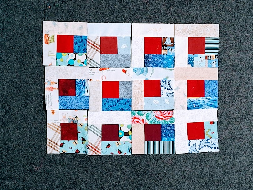 the beginning of blue and white log cabin blocks with red centers