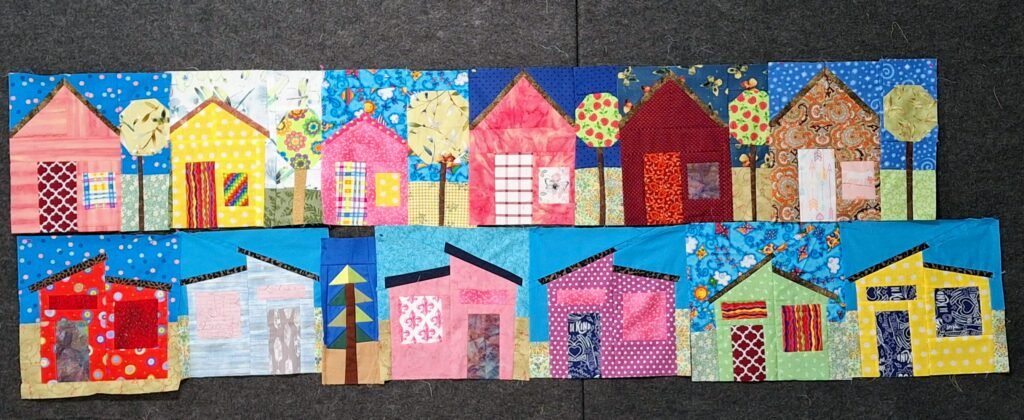 12 house blocks in bright fabrics divided into two horizontal rows of six