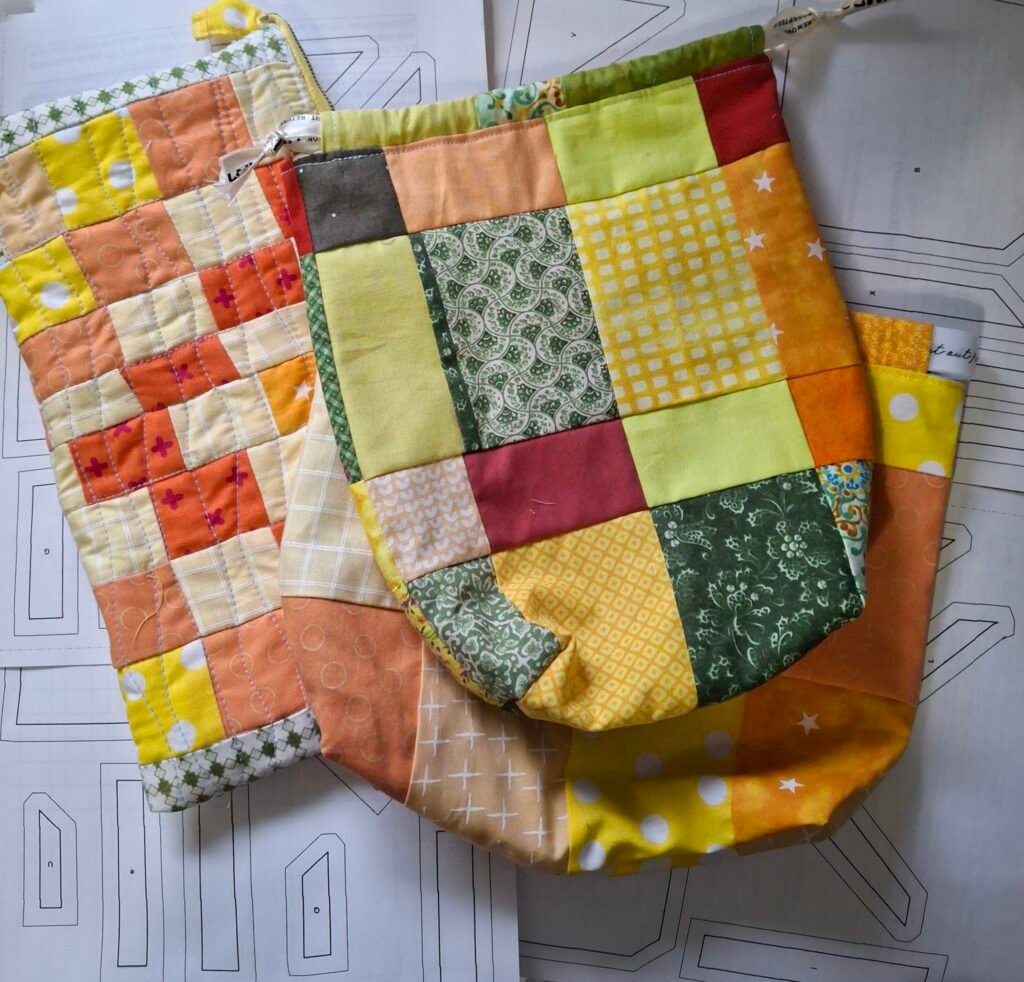 Three small citrus patchwork bags the author made in red, green, and orange. 