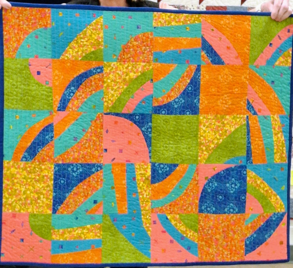 A modern quilt with curves in bright summery colors.