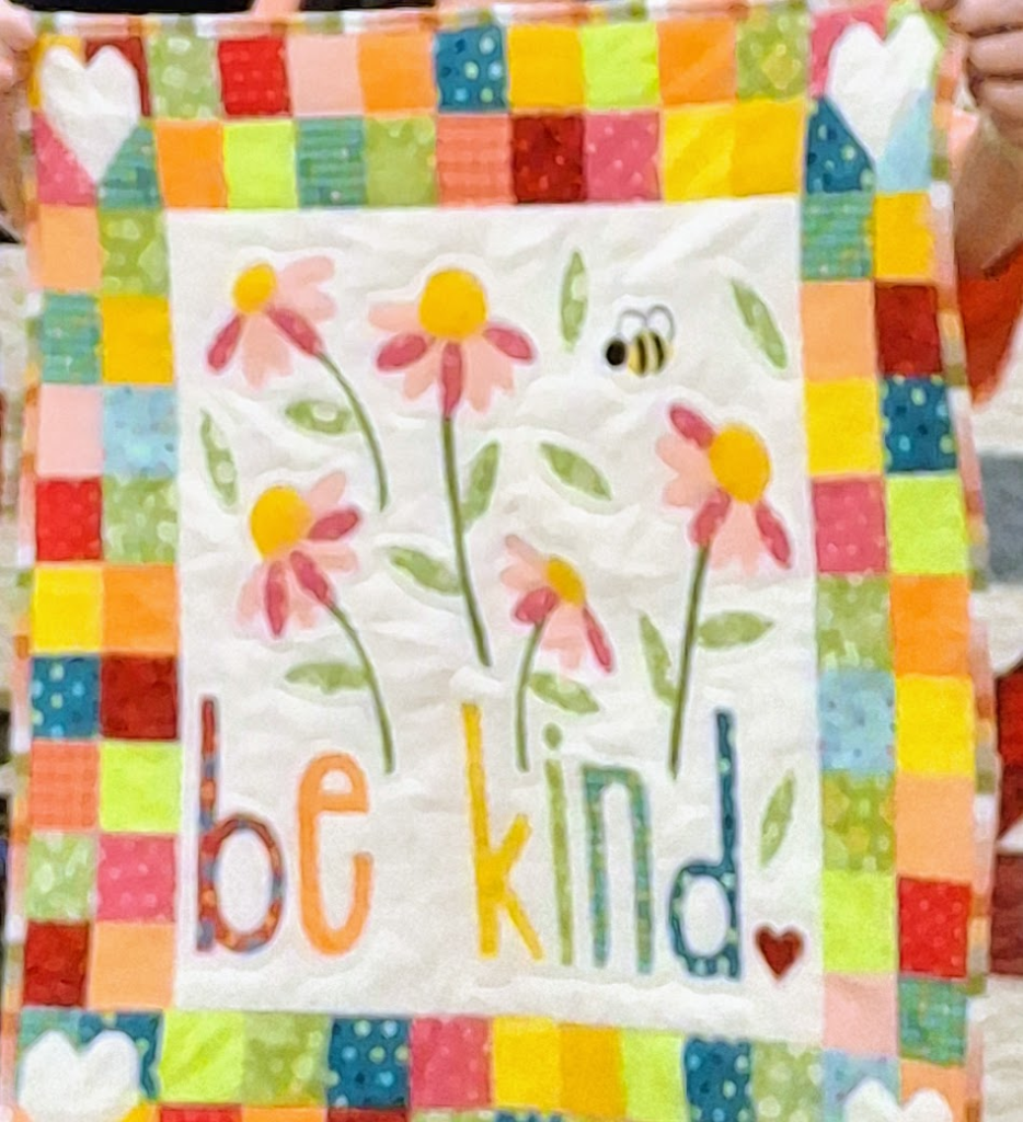 A bright modern quilt for the maker's mother. It has zinnias and "Be Kind" appliques