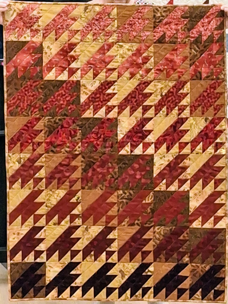 Red, brown and yellow "Crown of Thorns" blocks on a large quilt.