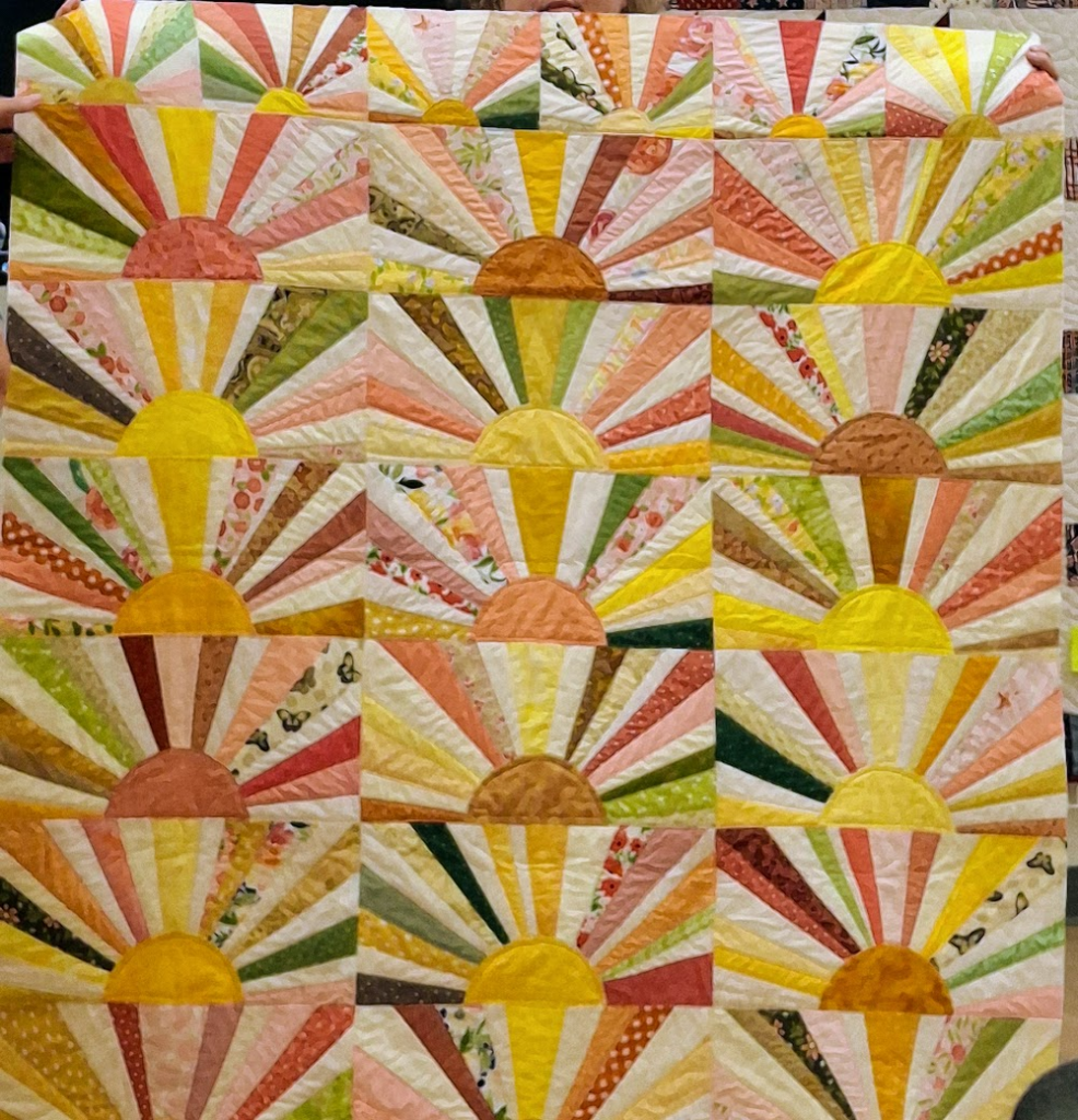 Sunrise quilt... the rays are in yellows, pale greens, oranges, and reds.