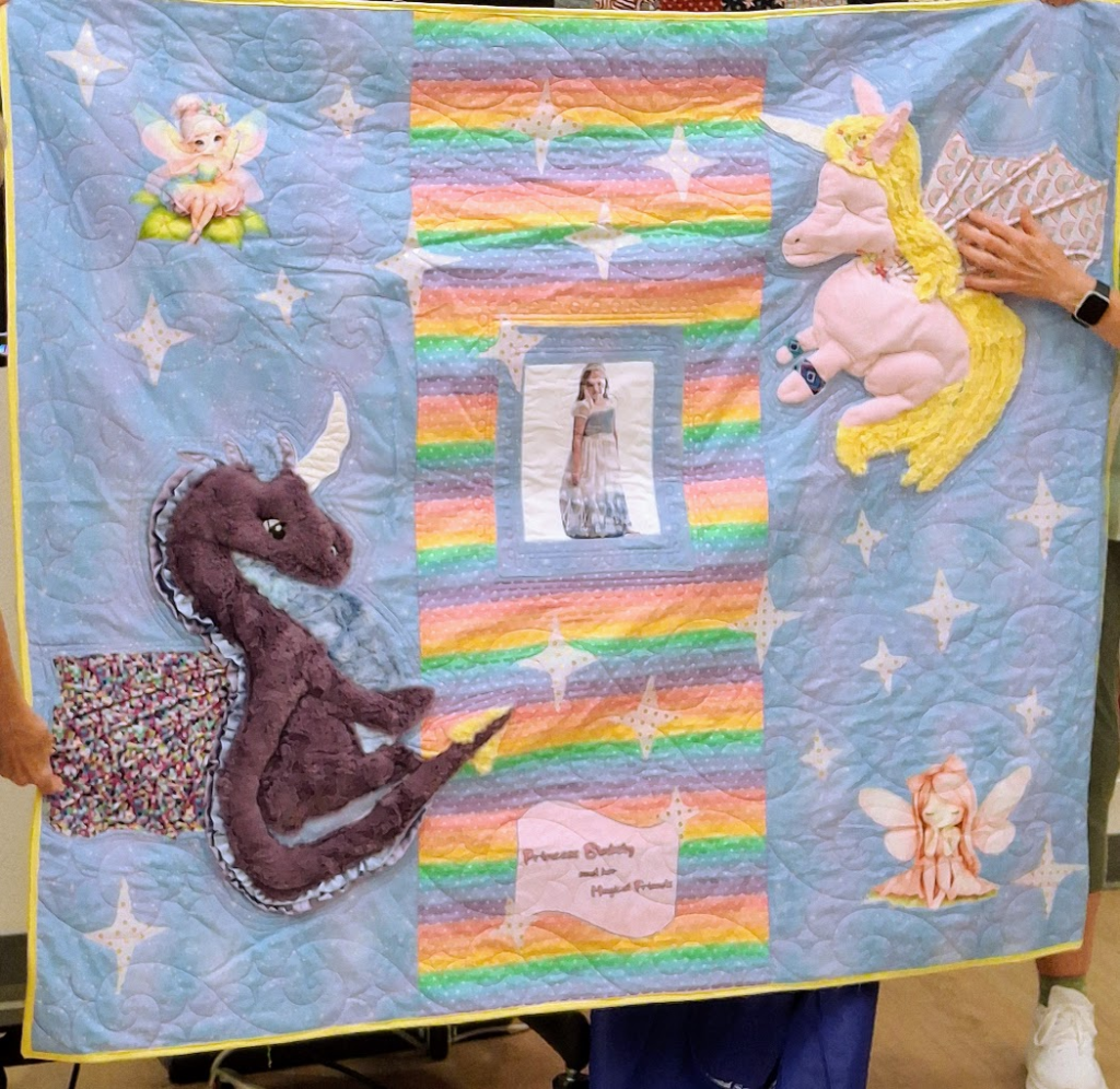 A little girl's princess quilt with 3D items such as a unicorn and dragon.