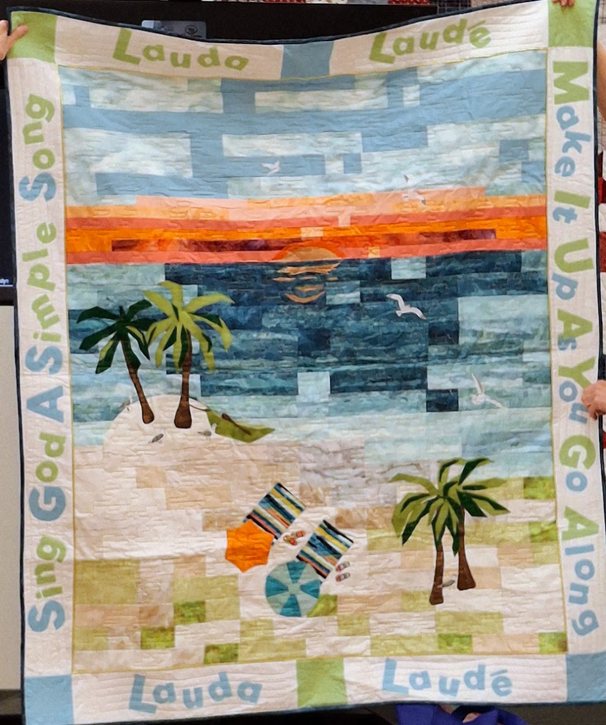 A summer quilt with a scene of the beach and water using modern applique and colors.