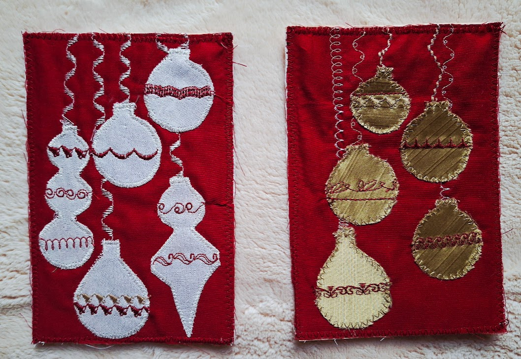 A photo of two completed postcards one silver ornaments on red satin, and one with gold ornaments on red satin.